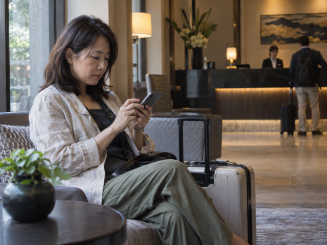 旅客在酒店大堂查看手机预订信息的真人摄影风格 AI 示意图